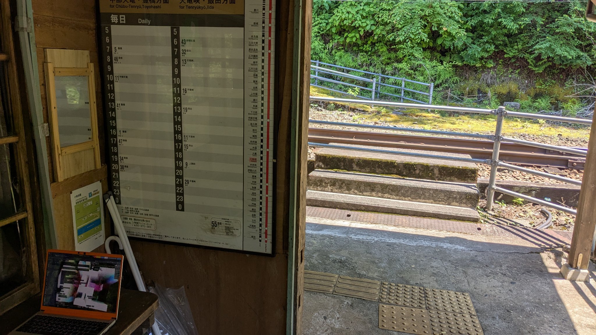 Figure 3: Joining the pastagang room from Kowada station, Japan. A photo taken inside an old wooden building at the station. There is a timetable on the wall, showing infrequent services. There is a laptop running nudel on the counter.